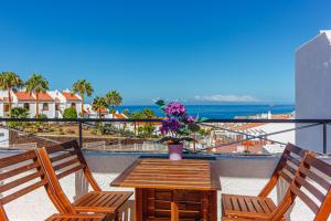 - un balcon avec 2 chaises et une table fleurie dans l'établissement Villas canarias con vista al mar, à Adeje