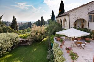 an outdoor patio with an umbrella and a garden at Villa il Galero in Asolo