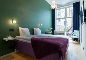um quarto com uma cama grande e um cobertor roxo em Hellstens Glashus em Estocolmo