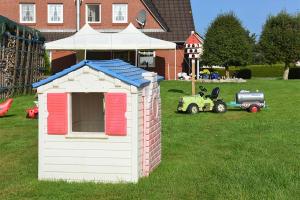 a small play house in a yard with a tractor at Ferienhof zur alten Linde in Holtgast