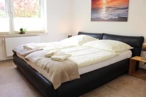 een groot bed met witte lakens en kussens erop bij Ferienhaus Wiedingharde II in Tating