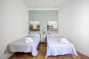 two beds in a room with white walls and wooden floors at Apartamentos Dali Madrid in Madrid