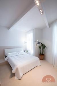 a white bedroom with a white bed and a plant at The Sunset Suite Vernazza in Vernazza