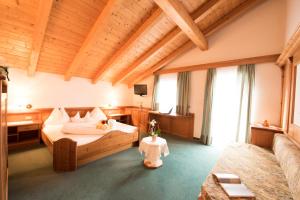 a large room with a bed and a desk and windows at Villa Rier in Siusi