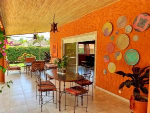 a dining room with an orange wall with a table and chairs at Safari Village Saly in Saly Portudal