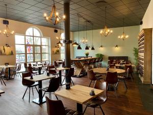 a restaurant with wooden tables and chairs and chandeliers at Hotel Schaumburg in Holstebro