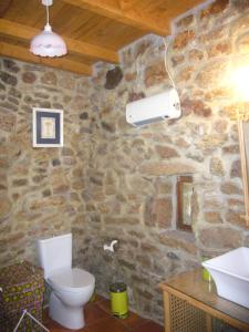 a stone bathroom with a toilet and a stone wall at Casa do Monge in Leomil