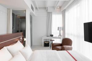ein Schlafzimmer mit einem Bett, einem Stuhl und einem TV in der Unterkunft Ruby Lotti Hotel Hamburg in Hamburg
