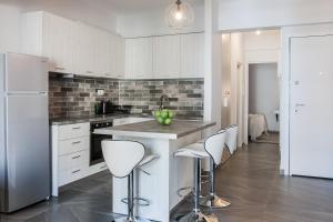 a kitchen with white cabinets and a island with bar stools at Urban & Cozy 1BD Apartment in Ampelokipoi Area by UPSTREET in Athens