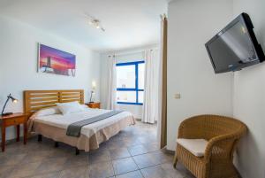 a hotel room with a bed, tv and a desk at Villas Puerto Rubicon in Playa Blanca