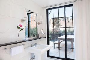 baño blanco con lavabo y ventana en The Broome en Nueva York