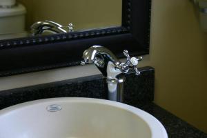 a bathroom sink with a faucet and a mirror at Villa Le View Guesthouse in Durban