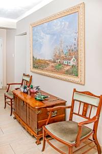 a room with a desk and two chairs and a painting on the wall at Villa Le View Guesthouse in Durban