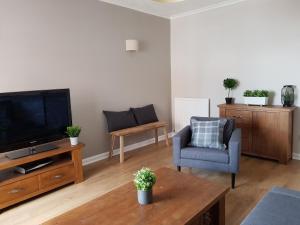 uma sala de estar com uma televisão e uma cadeira em The Abercromby Townhouse - Close to Merchant City em Glasgow