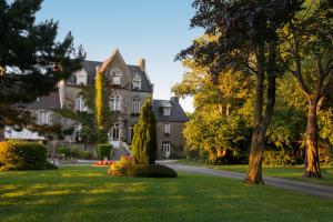 a large house with a lawn in front of it at Manoir de la Roche Torin, The Originals Relais in Courtils