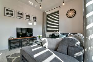 a living room with a couch and a clock on the wall at Old Town LTC - Apartments Starówka Panieńska in Gdańsk