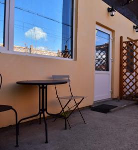 einen Tisch und Stühle neben einem Gebäude mit Fenster in der Unterkunft Victoriei 35B in Curtea de Argeş