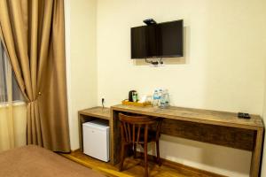 a room with a desk with a television on the wall at Irmisa Hotel Tbilisi in Tbilisi City