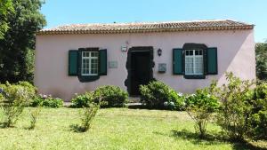 a small house with green shutters and a yard at Casa das Lapinhas in Lagoa