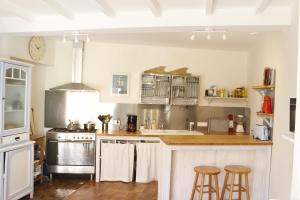 a kitchen with white cabinets and bar stools at La villa tamaris maison à partager in Vieux-Boucau-les-Bains