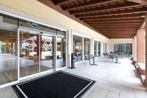um pátio com portas de vidro, mesas e cadeiras em B&B Hotel Affi - Lago di Garda em Affi