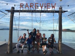 un grupo de personas posando bajo un cartel en un muelle en Hub of Joys Hostel en Ko Lanta