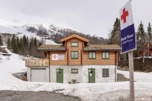 une maison en rondins avec des portes vertes dans la neige dans l'établissement Røde Kors ground floor, à Brunstad