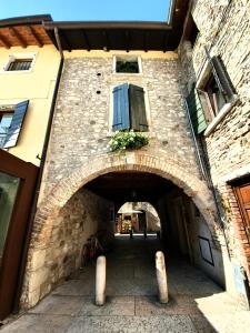 une arche dans un bâtiment en pierre avec une fenêtre dans l'établissement Appartamenti San Francesco, à Lazise