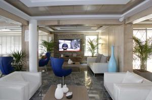 a living room with white furniture and a tv at Glaros Royal Beach Hotel in Hersonissos +46 photos