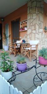 eine Terrasse mit Topfpflanzen sowie einem Tisch und Stühlen in der Unterkunft The House At The Pines in Péfka