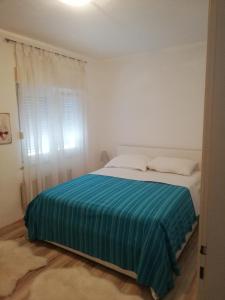 a bedroom with a bed with a blue blanket on it at Sweet Home Zadar in Zadar