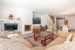 Una sala de estar con un sofá y un televisor. en Magnifica Moradia V4, en Casal da Lagoa Seca