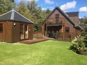 a large wooden barn with a patio and yard at La Fortuna Lodges in Stirling