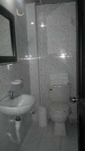 Baño blanco con aseo y lavamanos en Hotel Vermon Armenia, en Armenia