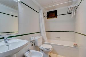 
a white toilet sitting next to a bath tub in a bathroom at Hotel Sis Pins in Port de Pollensa
