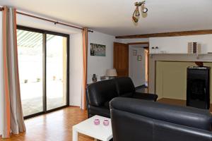 sala de estar con sofá de cuero negro y mesa en Etang Lassalle en Lamazère