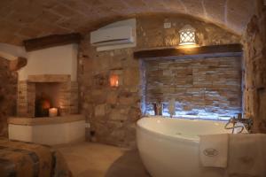 a bathroom with a bath tub and a stone wall at HolidayMonopoli in Monopoli