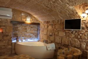 a bathroom with a tub and a tv on a stone wall at HolidayMonopoli in Monopoli