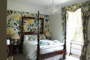 a bedroom with a bed with floral wallpaper and a chandelier at Bank House B and B in Penrith