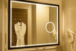 a bathroom mirror with a white robe on a rack at Hm Commerce Hotel in Ankara