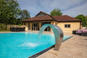 a pool with a water fountain in front of a house at Charlton court in Radstock