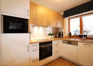 a kitchen with white cabinets and a stove top oven at Landhaus Am Schelmenhag 13a in Oberstdorf