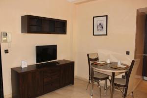een woonkamer met een tafel en een televisie en een tafel en stoelen bij Studio Salmiya Dune in Marrakesh