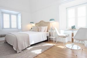 um quarto branco com uma cama, uma mesa e cadeiras em Lavradores Boutique Guesthouse em Évora