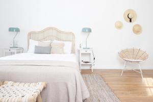 um quarto branco com uma cama grande e uma cadeira em Lavradores Boutique Guesthouse em Évora