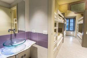 een badkamer met een glazen wastafel in een kamer met een stapelbed bij Little Italy Boutique Hostel in Perugia