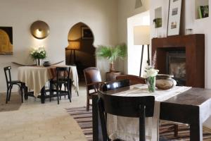 sala de estar con mesa, sillas y chimenea en Le Petit Hôtel du Flouka, en Lalla Takerkoust