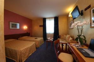 una camera d'albergo con 2 letti e una scrivania di Hotel Abacus a Porto Mantovano