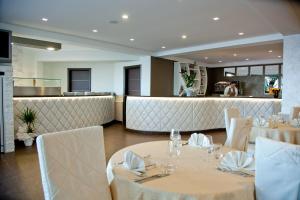 un ristorante con tavoli e sedie bianchi e un bar di Hotel Melissa a Torre Melissa