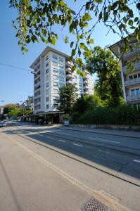 an empty street with a tall white building at PABS Résidences - Weinbergstrasse 68 (2ML) in Zurich